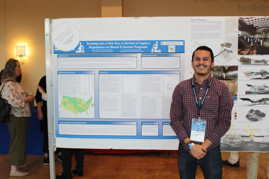 Person poses in front of their presentation at symposium